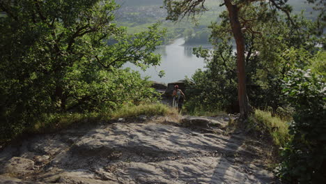 Un-Joven-De-Espalda-Camina-Caminando-Por-Un-Sendero-De-Montaña-Con-El-Pecho-Desnudo,-Gorra-Snapback,-Equipo-De-Montañero,-Escalada-Al-Aire-Libre,-Buscando-Una-Pared-Para-Escalar,-Clima-Soleado-De-Verano-En-Durnstein,-Austria,-Europa