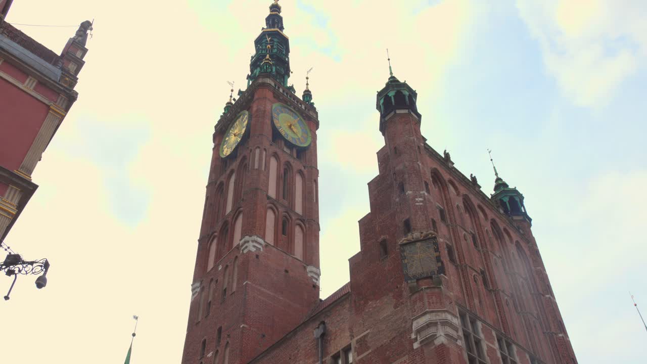 Wander through the lively streets of Gdańsk's old town, admiring the stunning architecture, historic church, and the crowd of people enjoying their day.