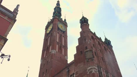 wander through the lively streets of gdańsk's old town, admiring the stunning architecture, historic church, and the crowd of people enjoying their day.