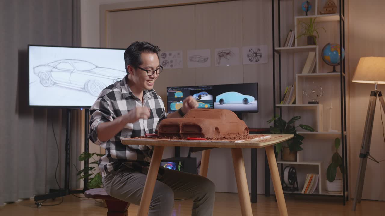 hombre asiático diseñador de automóviles celebrando el éxito trabajando en la escultura de arcilla de automóviles por rastrillo o alambre en el estudio