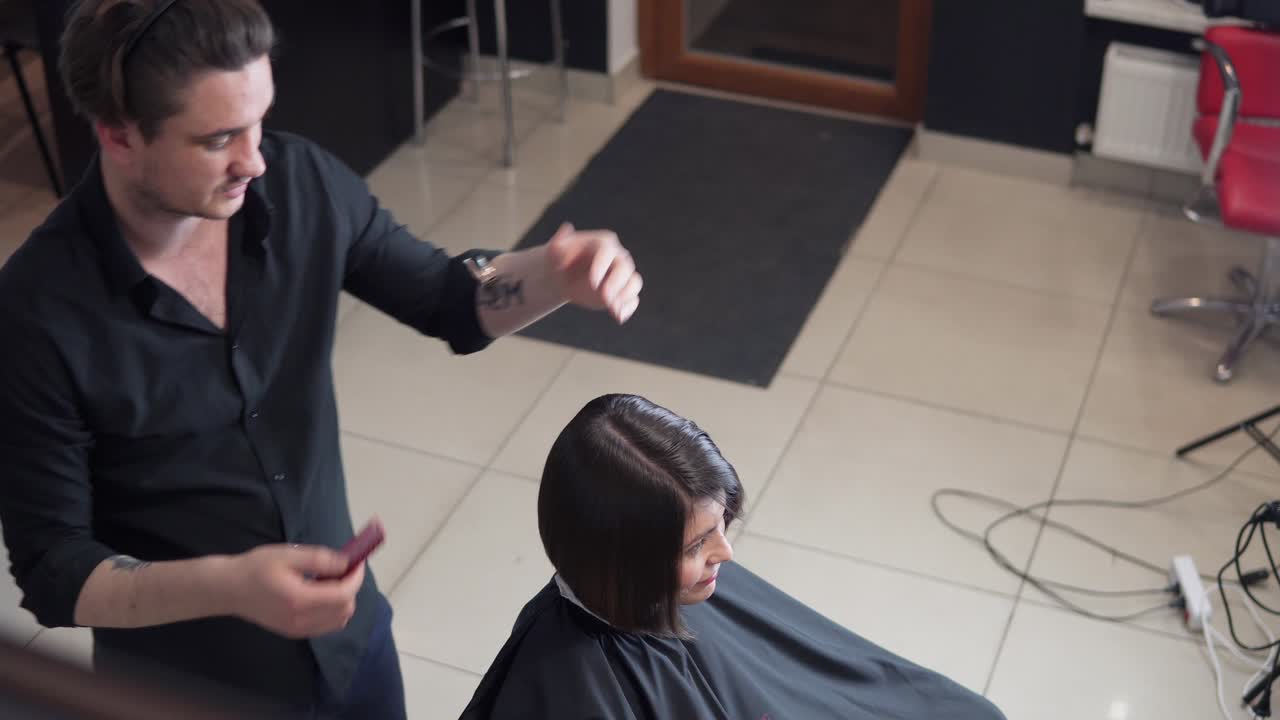 Professional hairdresser, stylist makes professional hairstyle of young woman in beauty studio. Beauty and haircare concept
