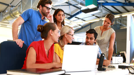 businesspeople interacting while using laptop