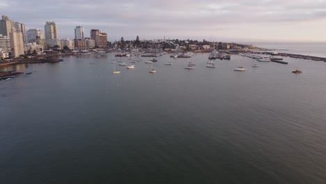 Aerial-approach-of-Punta-del-Este-city-in-Uruguay-at-sunset-with-port-district-and-skyscrapers-in-background