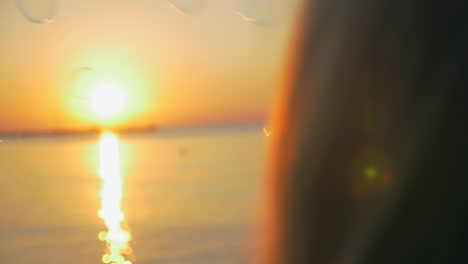 girl blowing bubbles at seaside during sunset