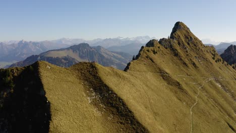 Aerial-reveal,-hikers-on-the-summit-and-the-Alps-in-the-background,-autumn-colors-"La-Cape-au-Moine"-Vaud---Switzerland