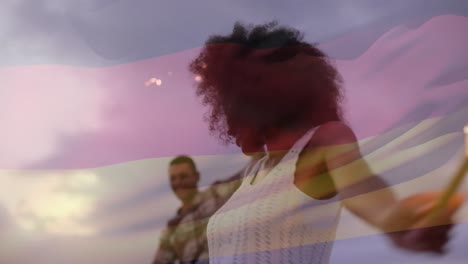 Animation-of-waving-germany-flag-over-group-of-diverse-friends-on-the-beach