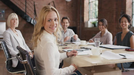 portrait of a confident young business woman  at boardroom table in slow motion turning around and smiling