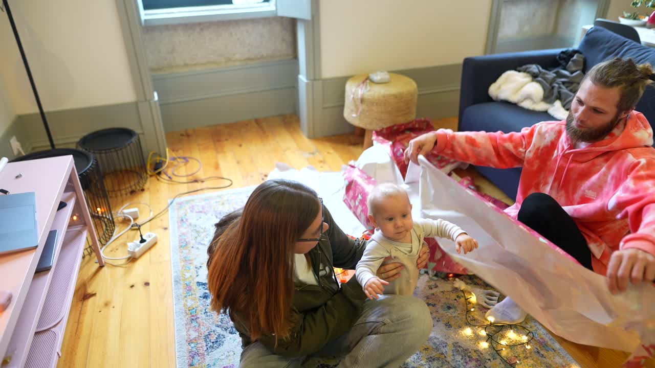 가족이 아기와 함께 크리스마스 선물을 풀고 있습니다.