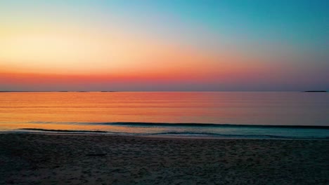 colorful beach sunset in saco, maine with bright colors reflecting off calm rippling ocean waves along the new england atlantic coastline