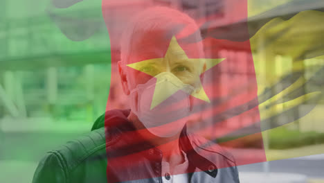 Animation-Der-Flagge-Kameruns,-Die-Während-Der-Covid-19-Pandemie-über-Einem-Mann-Mit-Gesichtsmaske-Winkt
