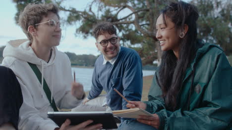 students doing college homework with digital tablet in the park