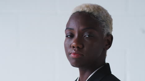 retrato de una joven mujer de negocios determinada vestida con traje de pie contra la pared blanca del estudio