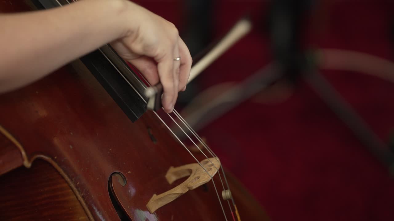 Detailed close up of a cellist's hand playing the cello with a bow