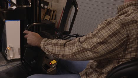 blue collar worker operating levers to lower forklift