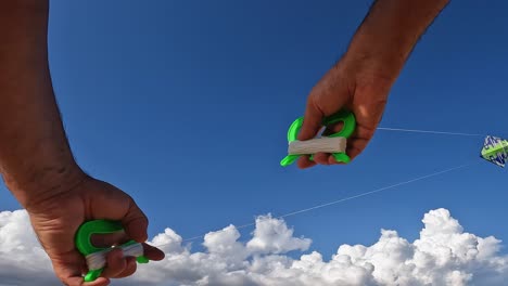 unusual perspective of hands flying green kite by holding green handles