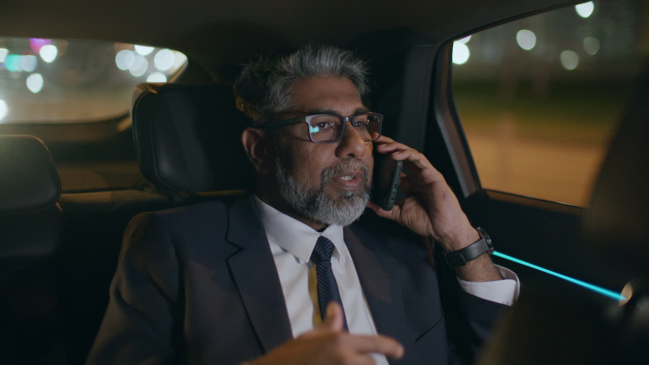 Middle Aged Businessman Talking on Smartphone while Riding in Backseat