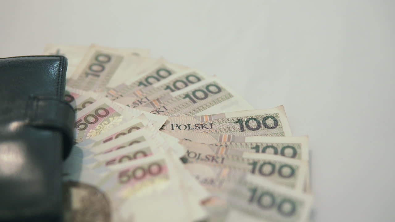 500 zloty polandia dan 100 zloty polandia berbaring di dekat dompet hitam di atas meja putih