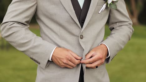 young man or groom in formal suit getting dressed and buttoning jacket outdoors 1080p 60fps