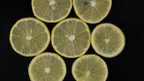 collection of fresh lemon slices on black background. rotation citrus fruit. top view.