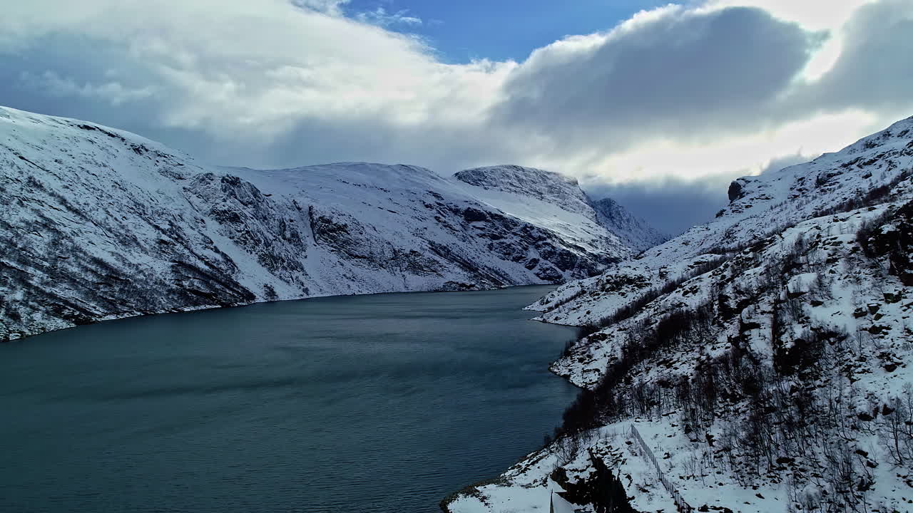 Aufsteigende Luftaufnahme von verschneiten Bergen und ruhigen Gewässern in den Fjorden Norwegens