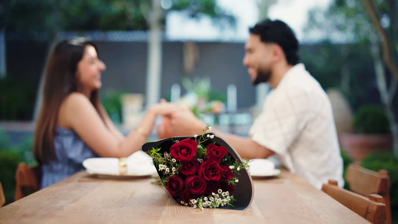 Coppia romantica che si tiene per mano ad un appuntamento con un bouquet di rose rosse