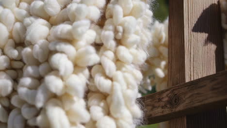 woven white and beige yarn drying on wooden frame
