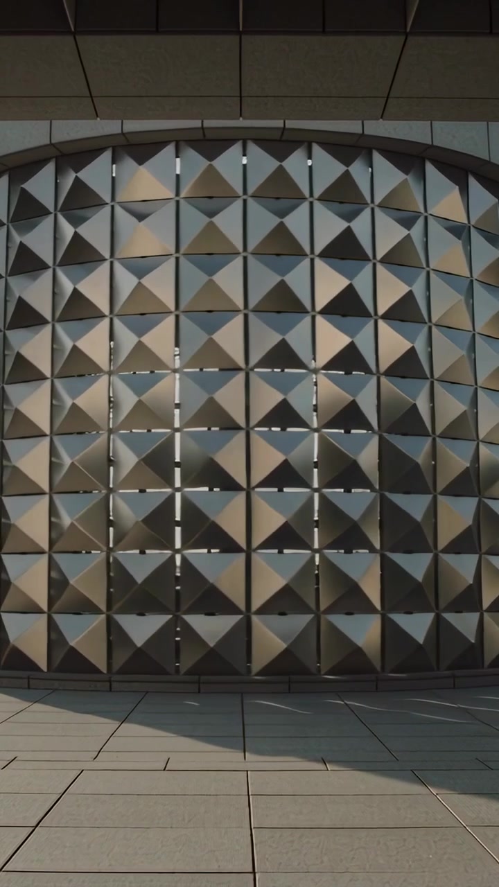 Vertical video: Start panning camera filming curved metal wall at plaza, showing shifting light
