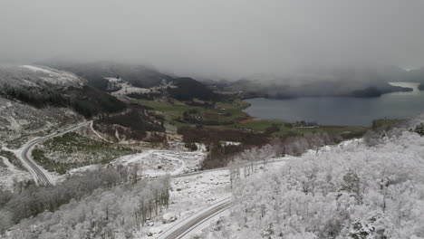 norwegian national road 13 crossing snowy landscape with fjord in background on cloudy day, norway