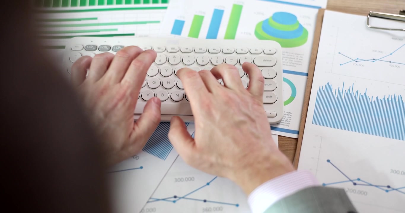 Kontormedarbejder skriver rapport på computerens tastatur, siddende ved skrivebordet