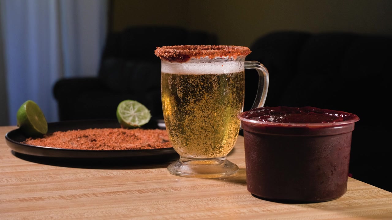 Bollicine di anidride carbonica salgono attraverso un bicchiere di birra ghiacciata prima che un uomo allunghi la mano e lo sollevi da un tavolo di legno.