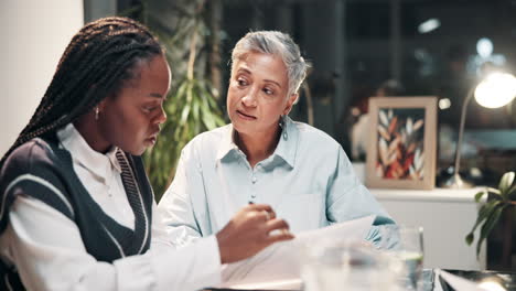 two businesswomen discussing documents at a table