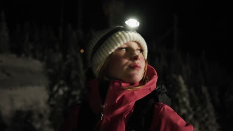 caucasian girl wearing a headlamp outdoors at night