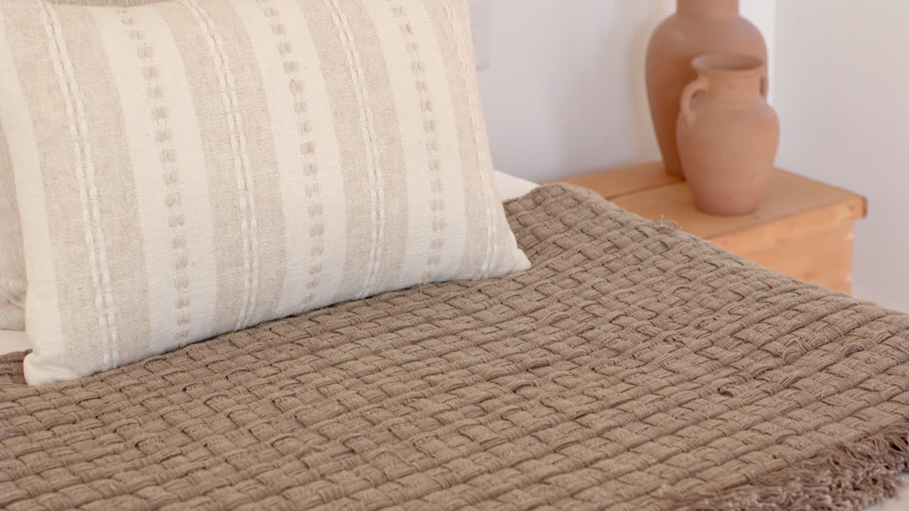 Cozy bedroom with decorative clay vases on wooden nightstand near bed, at home
