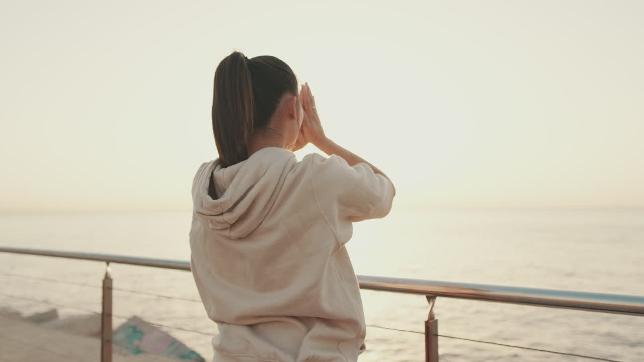 海辺で日の出を楽しむ女性
