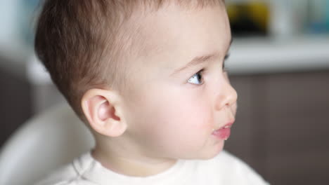 face of a lovely caucasian baby during meals. nice little boy with food around mouth. close up portrait.