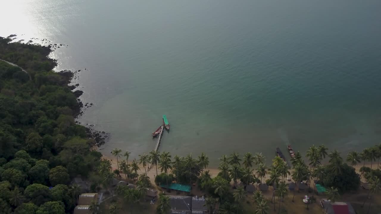 Aerial view of a tropical coast with a pier and boats