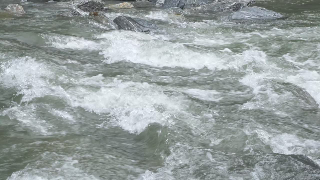 River Flowing With Stone Boulders And Stone Rapids In Haast, New Zealand