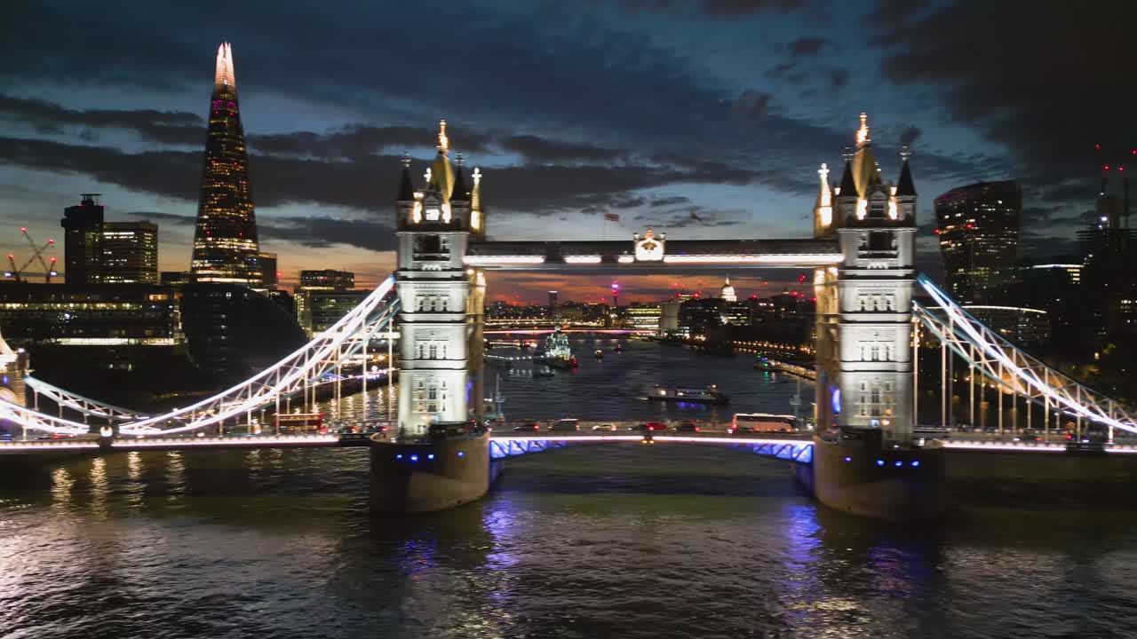 Aerial tracking shot in front of the illuminated Tower bridge, dusk in London, UK