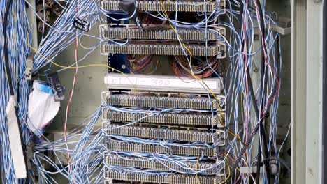 centralita eléctrica no en funcionamiento con cables de red y telefónicos sobresalientes en la calle