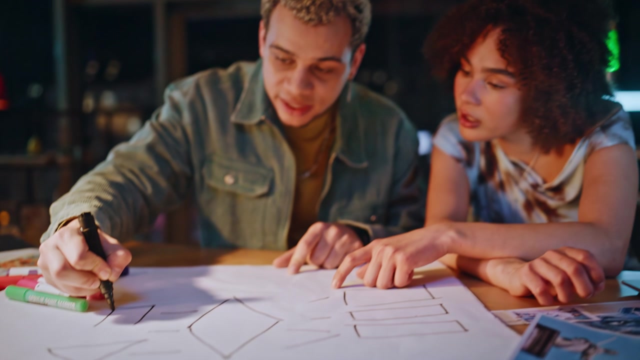 Designer che abbozzano wireframe su carta. Colleghi che pianificano un'app in studio di notte