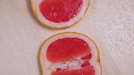 sliced ripe grapefruit under drops of water rotation close-up