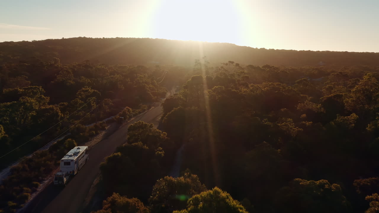 disparo aéreo, la caravana está viajando hacia el amanecer en un paisaje natural en el bosque