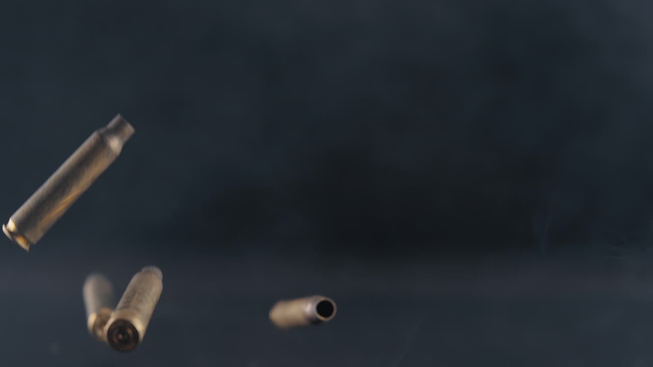 cartuchos de municiones gastadas cayendo a través del humo sobre una superficie brillante