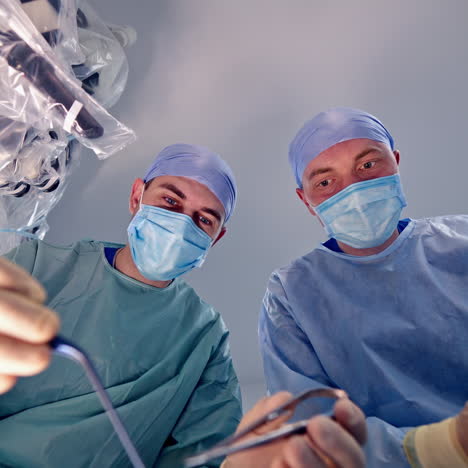 view from below on two surgeons faces while doing operation. happy doctors finishing the operation successfully in clinic.