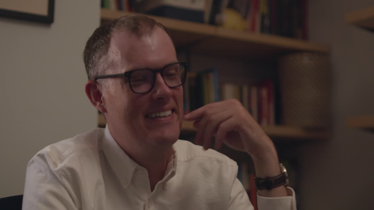 A professional in glasses counting from one to five on his fingers while mouthing the words and talking