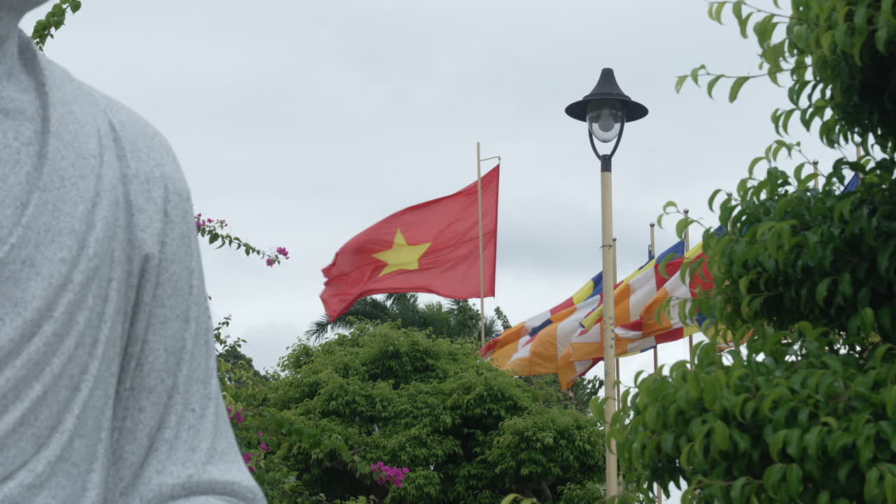 A view of Vietnam’s green landscape, with a statue and flags fluttering in the wind