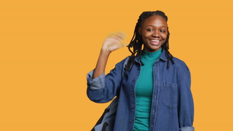 Portrait-of-chipper-girl-waving-hand,-gesturing,-studio-background