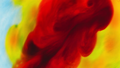 pintura o tinte rojo y amarillo caído en el agua contra un fondo blanco para crear un fondo de humo de colores giratorios