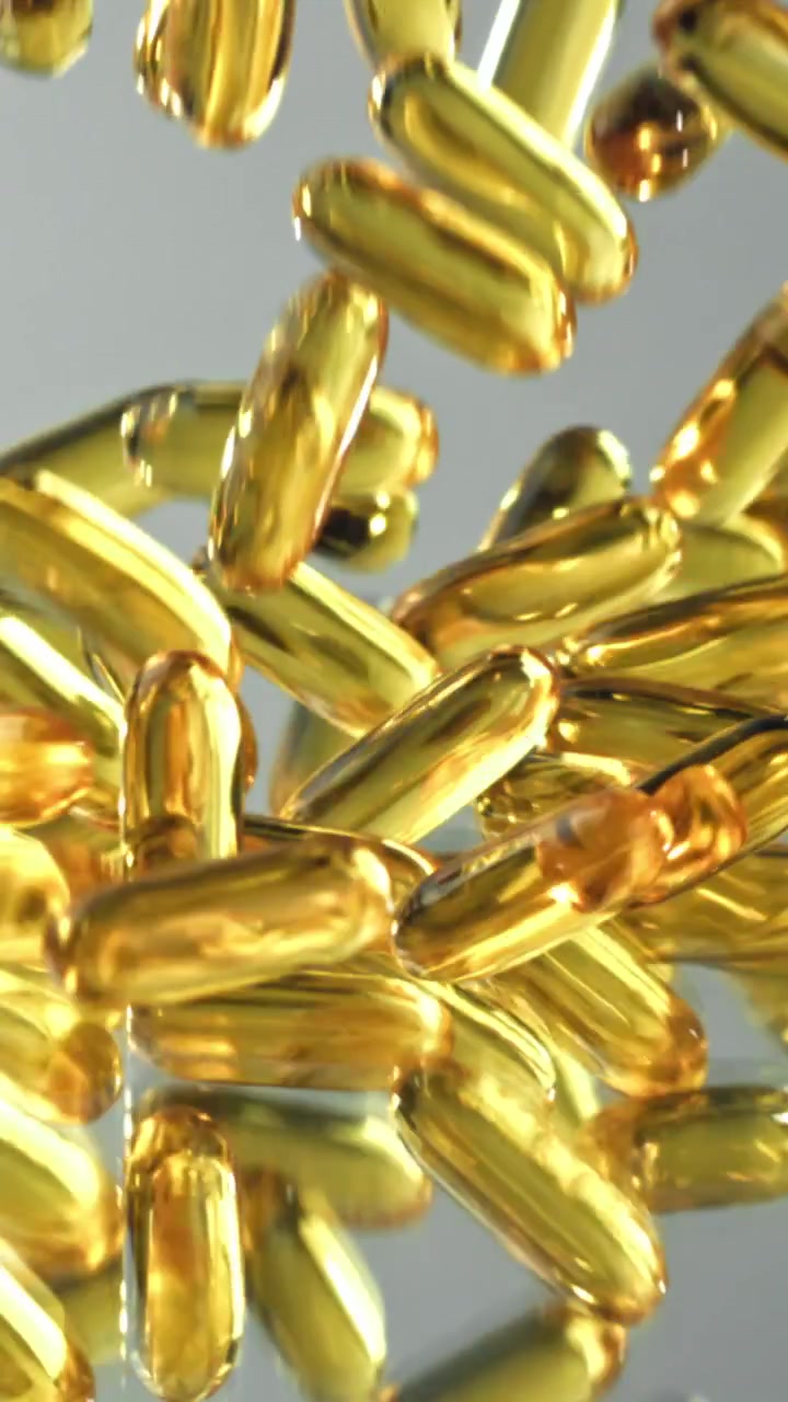 Capsule softgel di Omega 3 dorate che cadono e rimbalzano al rallentatore