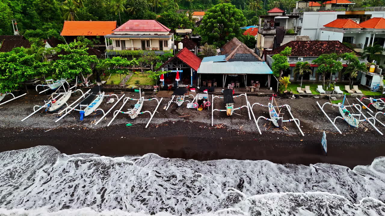 Vista aerea di una lunga fila di barche a bilanciere jukung bianche su una spiaggia di sabbia vulcanica nera di fronte al villaggio di Amed. Amed, Bali, Indonesia, Perahu Jukung.